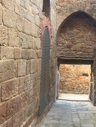 L'immagine mostra un vicolo stretto e in salita, pavimentato con pietre. Le pareti laterali sono fatte di massi di pietra grezza di diverse dimensioni.