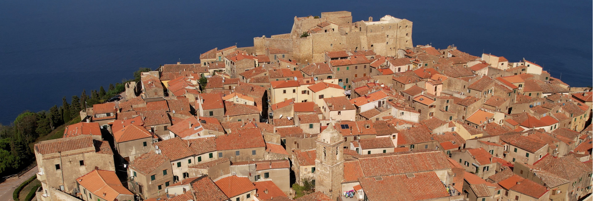 L'immagine mostra il borgo fortificato di Giglio Castello visto dall'alto circondato dal mare