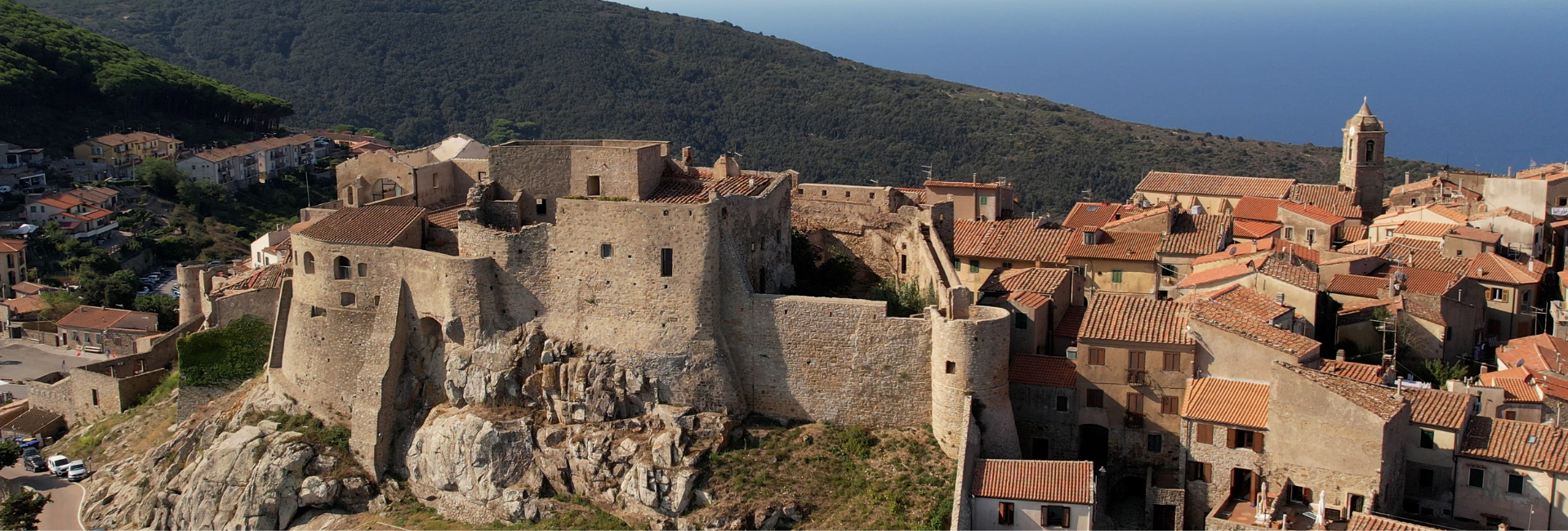 L'immagine mostra il borgo fortificato di Giglio Castello, situato sull'Isola del Giglio in Toscana, in una vista aerea.