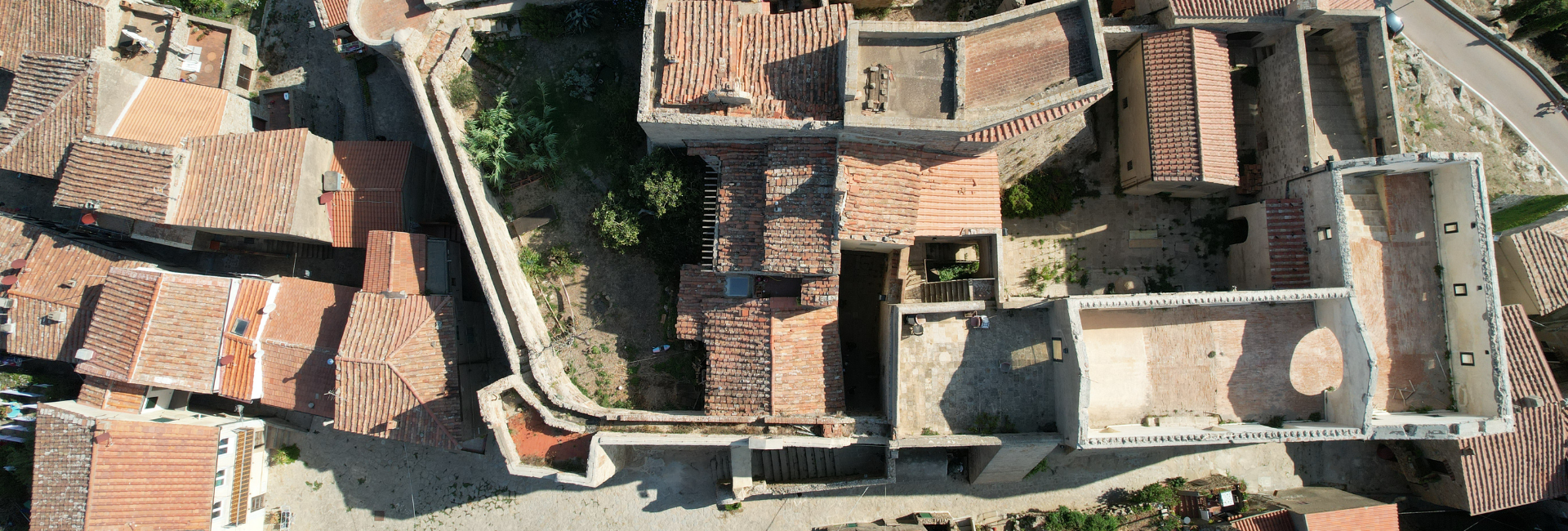 La foto, scattata da una prospettiva aerea, mostra un complesso di edifici tra cui la Chiesa ed il Cassero in pietra con tetti in tegole.