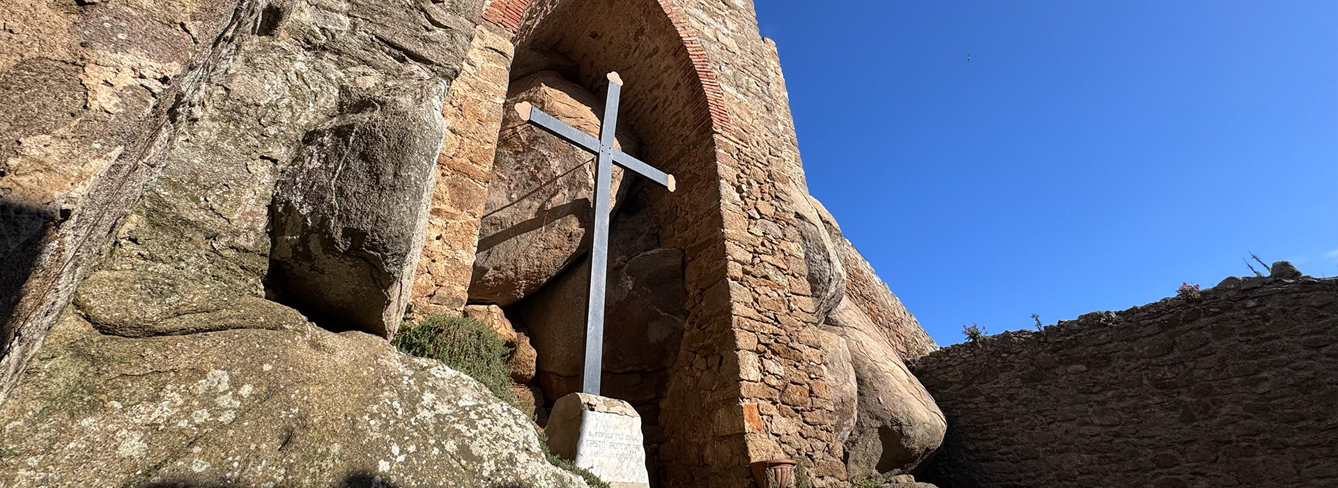 L'immagine mostra una grande croce scura di metallo.