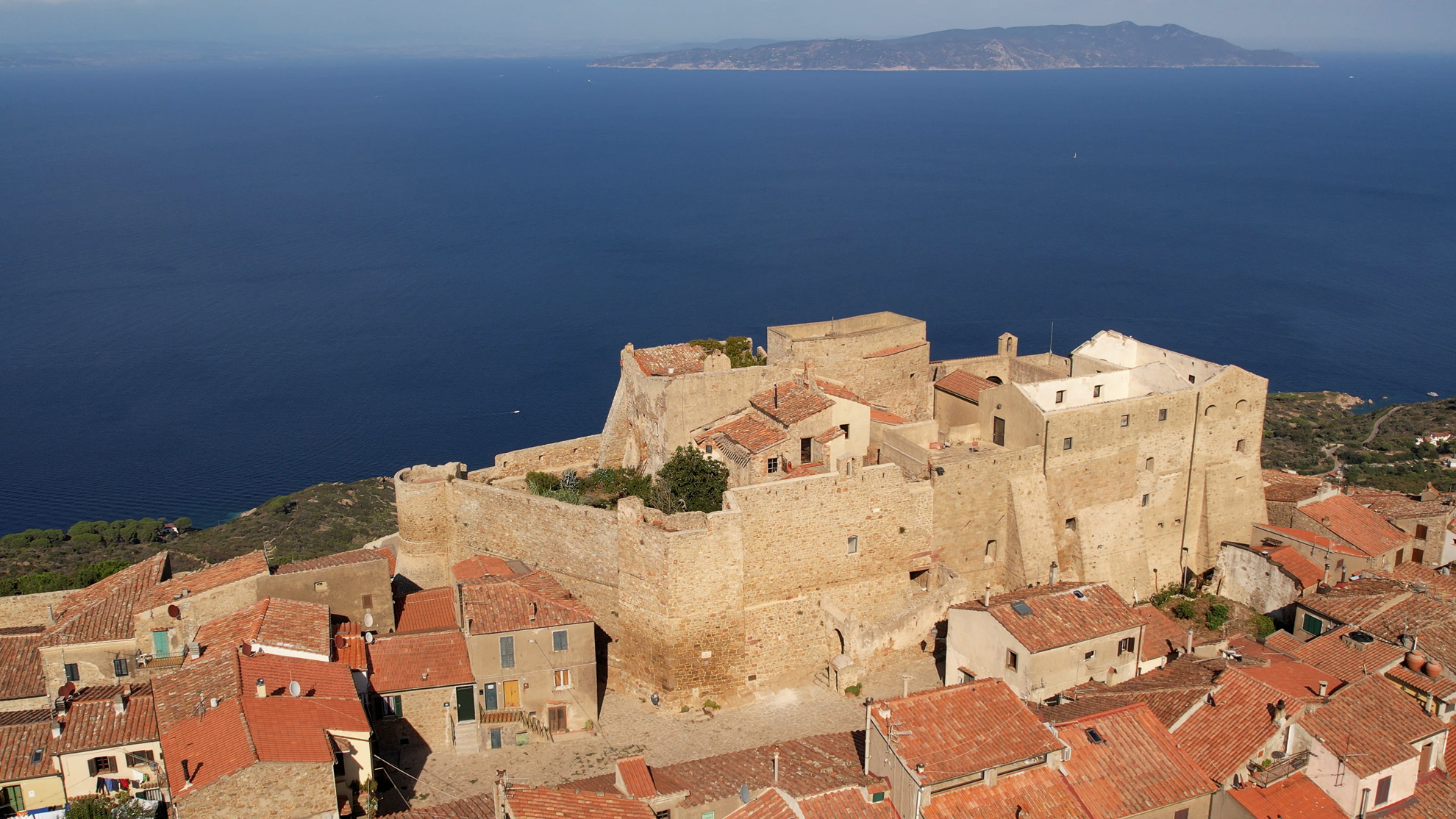 La vista aerea cattura il borgo mentre si estende sulla cima di una collina, circondato dalle sue antiche mura medievali.