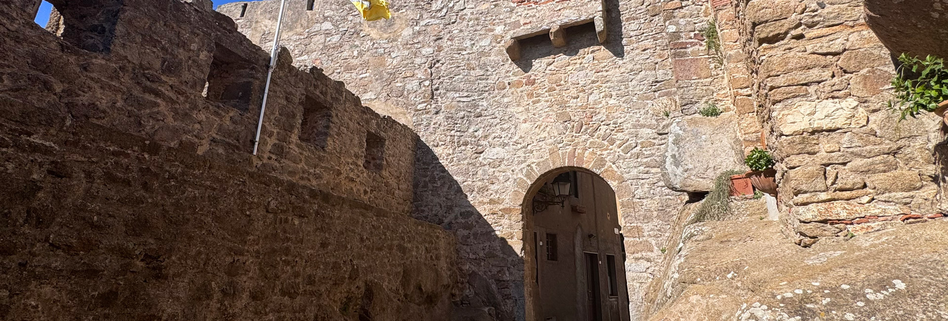 L'immagine mostra un vicolo in pietra che conduce ed attraversa un arco in pietra.