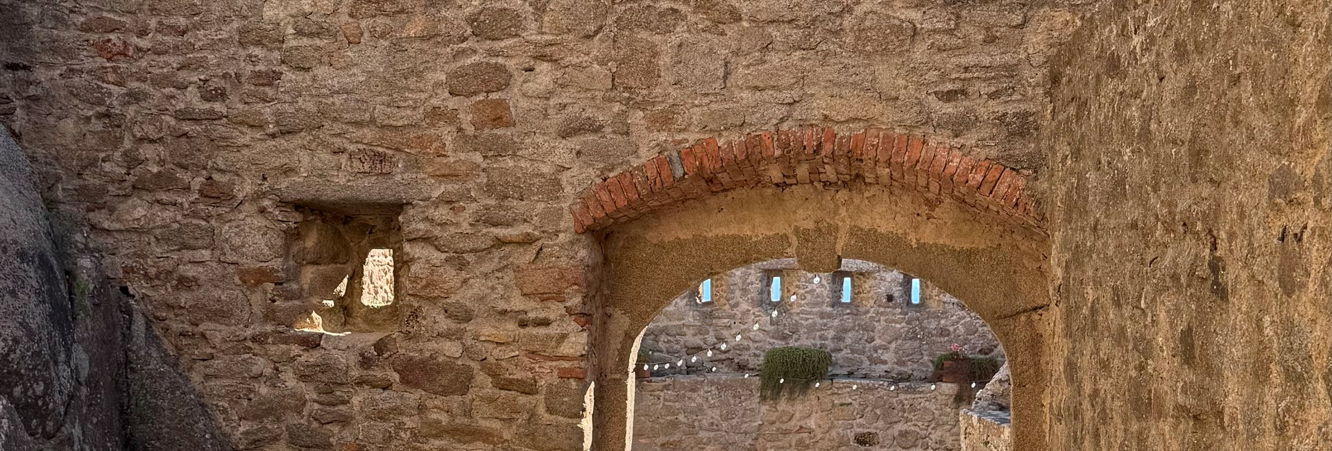 L'immagine mostra la parte alta un'arcata in pietra, con mattoni a vista nella parte superiore.