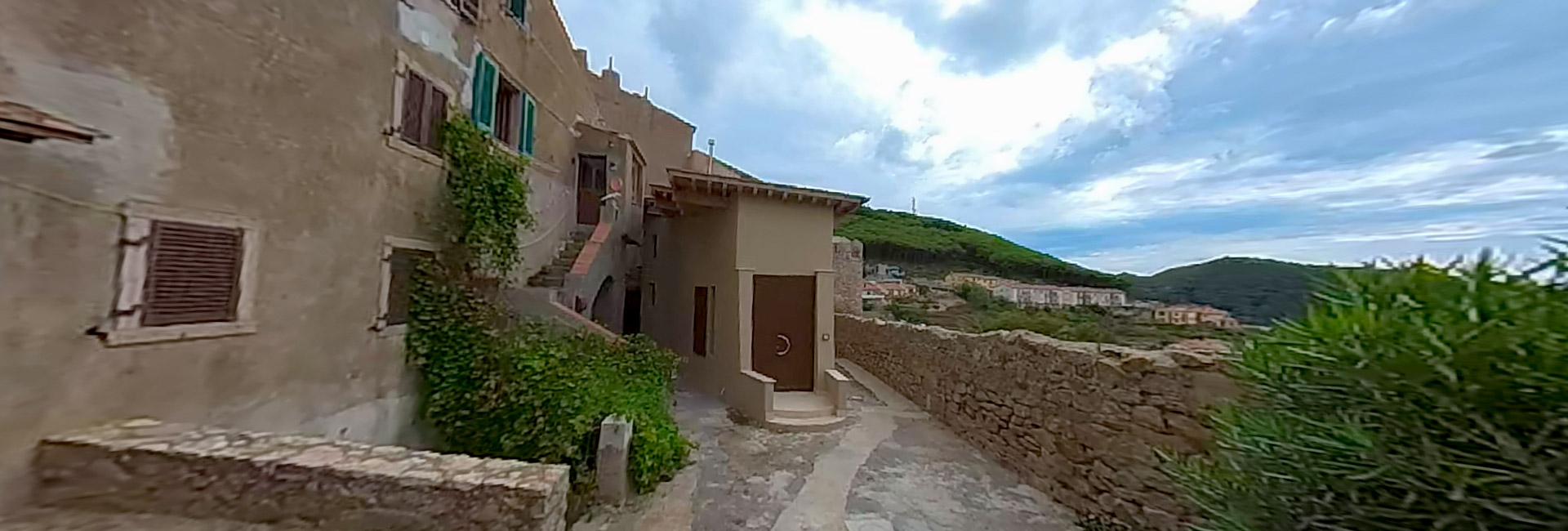 L’immagine mostra una piccola stradina di pietra con case sono costruite con muri in pietra e intonaco