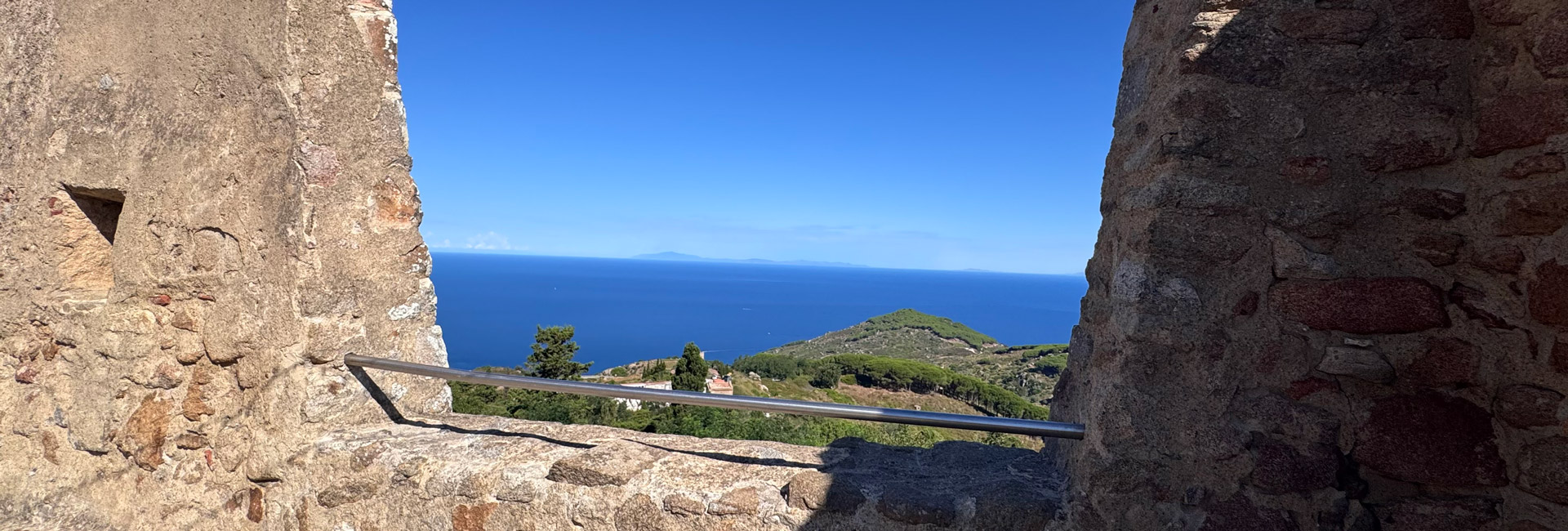 L'immagine ritrae una vista panoramica sul mare e su una parte di un promontorio della costa toscana